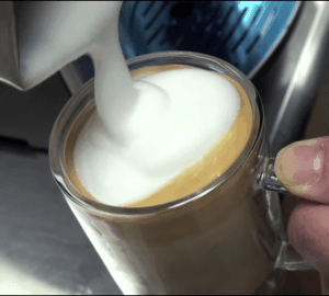Pouring latte in a glass mug